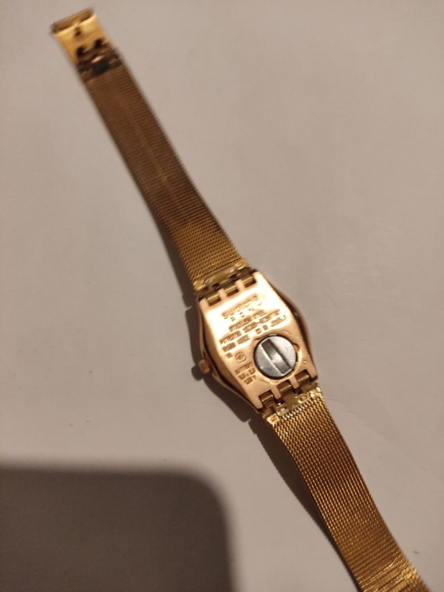 Reloj marca Swatch terminado en oro.