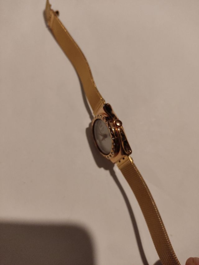 Reloj marca Swatch terminado en oro.