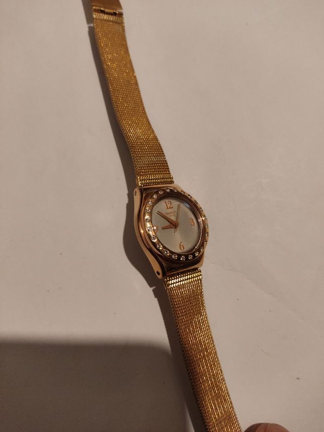 Reloj marca Swatch terminado en oro.