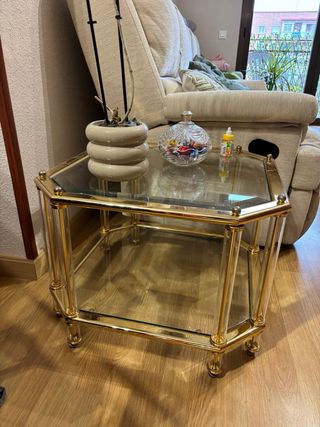 Conjunto de mesas de vidrio y metal dorado.
