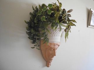 Escultura mujer jardinera pared plantas