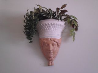 Escultura mujer jardinera pared plantas