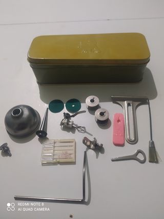 Caja metálica con accesorios de maquina de coser