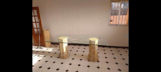 Mesa de cristal con patas de piedra