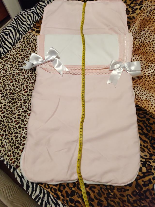 Saquito de bebé rosa y blanco y colcha