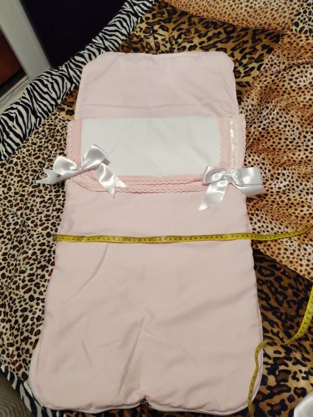 Saquito de bebé rosa y blanco y colcha