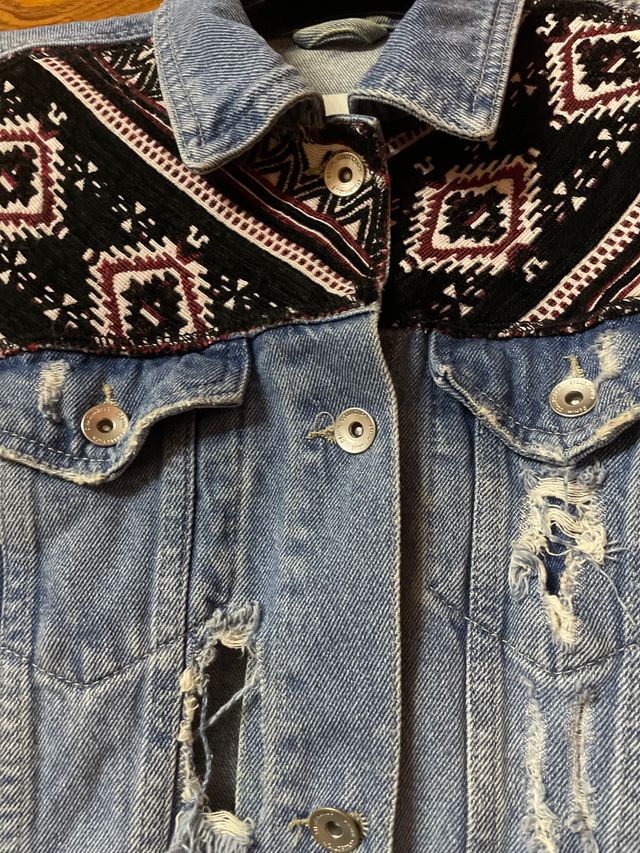 Cazadora vaquera azul con rotos de adorno