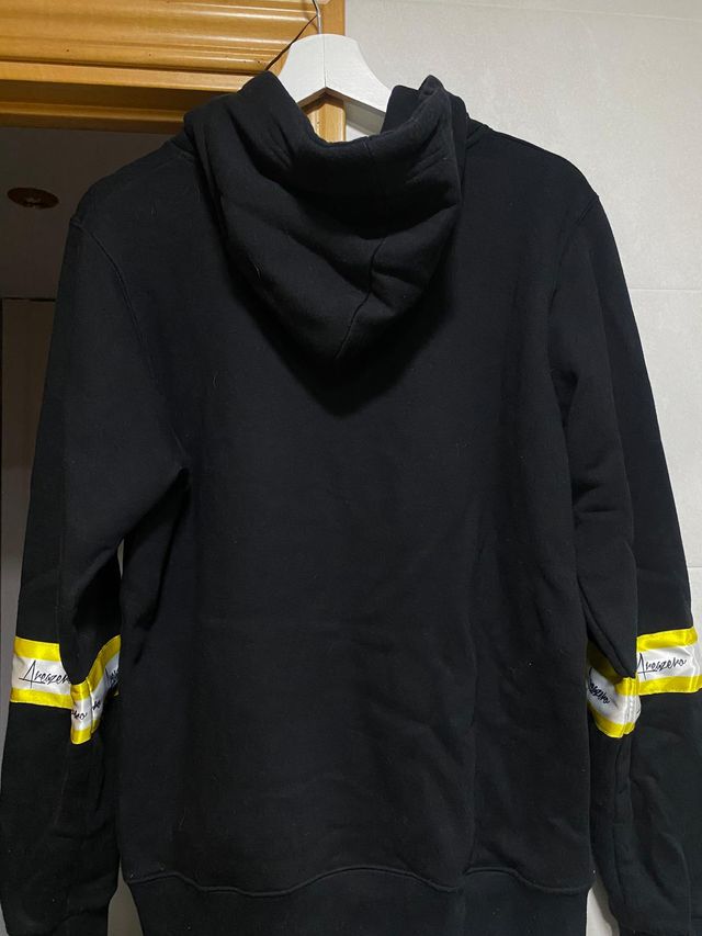 SUDADERA NEGRA Y AMARILLA CON CAPUCHA AREA ZERO