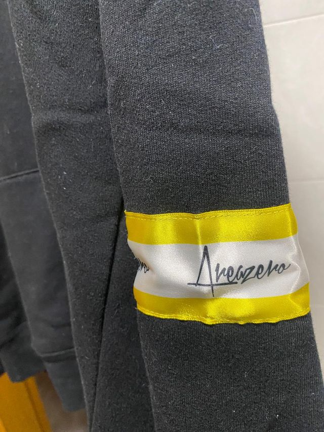 SUDADERA NEGRA Y AMARILLA CON CAPUCHA AREA ZERO