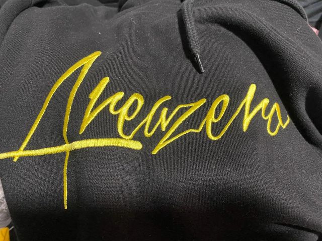 SUDADERA NEGRA Y AMARILLA CON CAPUCHA AREA ZERO