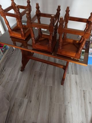 Mesa de cocina con su cristal y cuatro bancos.