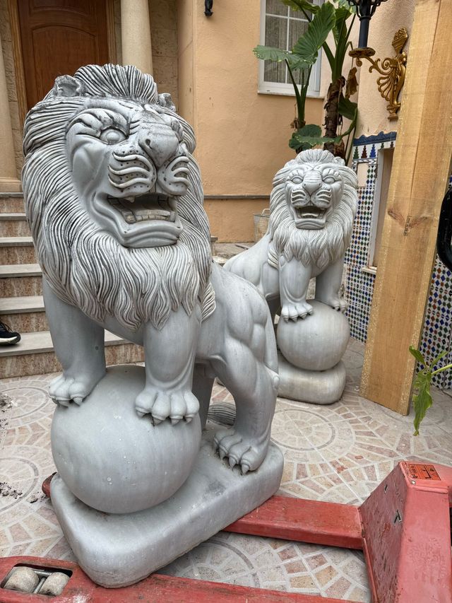 Pareja de esculturas de leones tallados en mármol.