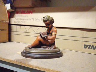 Figura niño leyendo escultura sobre base de madera