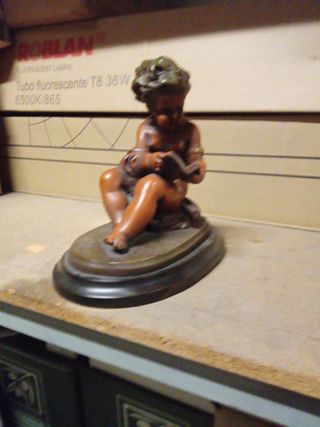 Figura niño leyendo escultura sobre base de madera