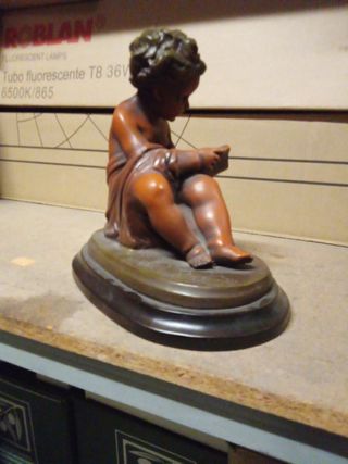 Figura niño leyendo escultura sobre base de madera