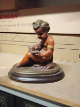Figura niño leyendo escultura sobre base de madera