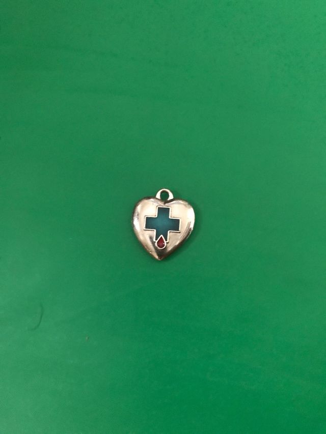 Corazon de metal con cruz verde ,no tiene marca