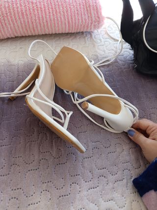Sandalias blancas altas se atan ala pierna..