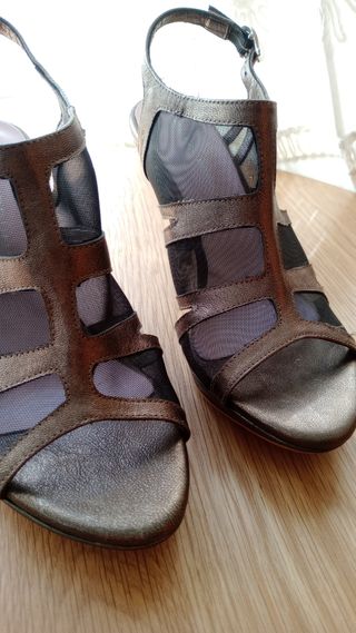 Sandalias doradas y con regilla negra de tacón.