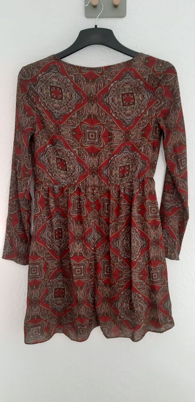 Vestido en tonos marrones y rojizos. Se ciñe un po