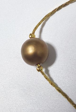 Gargantilla dorada con perlas de color bronce.