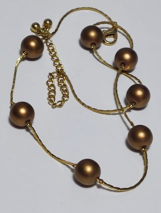 Gargantilla dorada con perlas de color bronce.