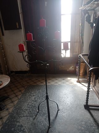 Candelabro antiguo metal negro y velones rojos.