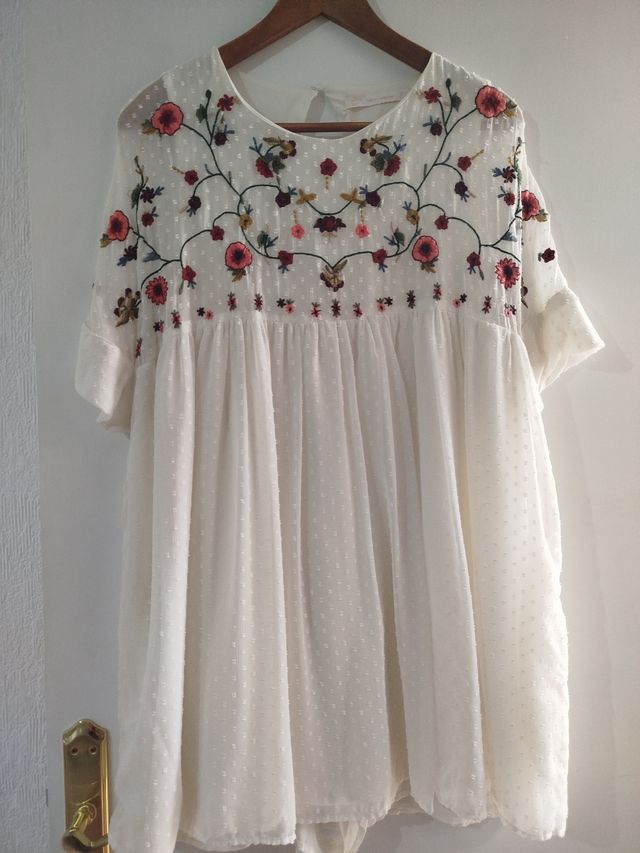 Vestido corto en color crudo con pantalón .