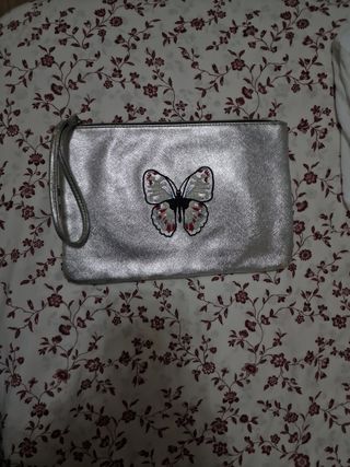 Bolso de mano plateado con mariposa