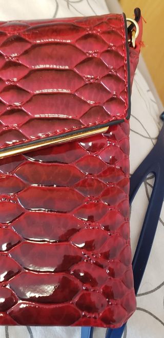 Bolso rojo tipo piel de serpiente.