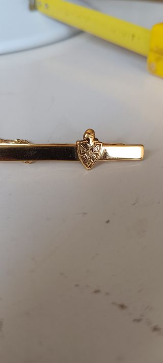 Pasador de corbata dorado con escudo