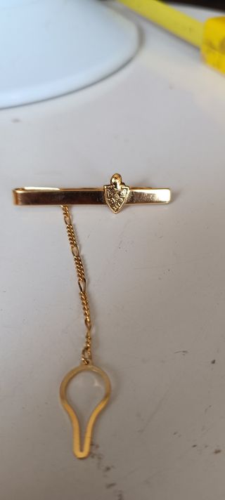 Pasador de corbata dorado con escudo