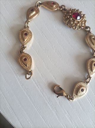 Pulsera dorada con piedras rojas