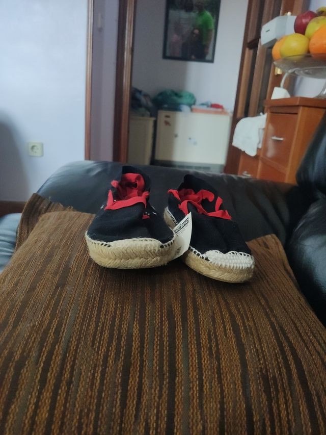 Alpargatas negras con lazo rojo.