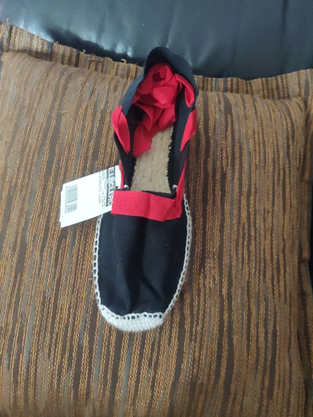 Alpargatas negras con lazo rojo.