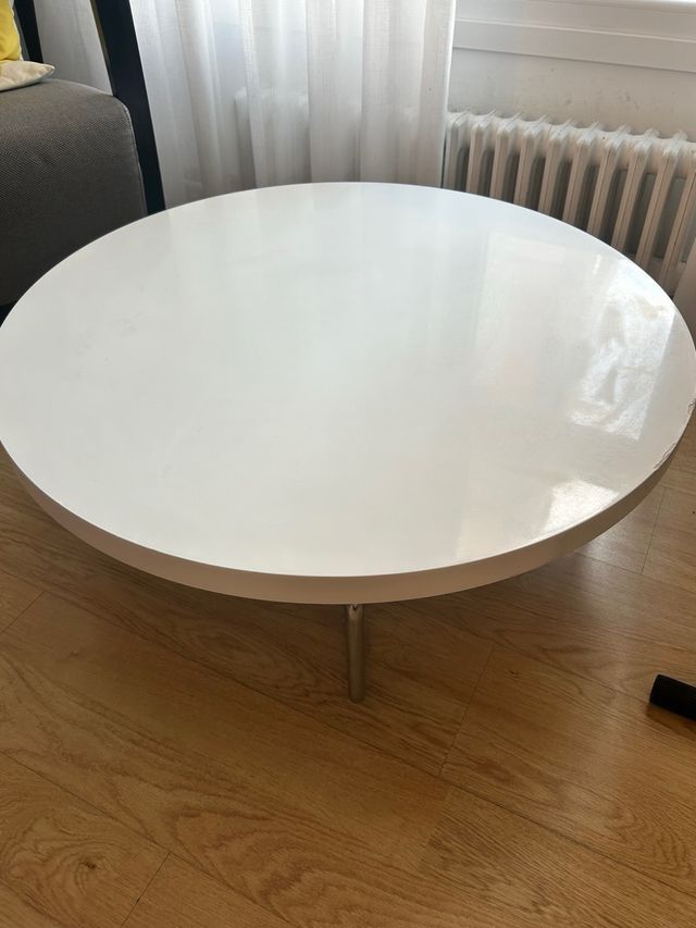 Mesa centro redonda blanca con patas de acero.
