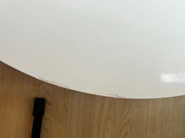 Mesa centro redonda blanca con patas de acero.