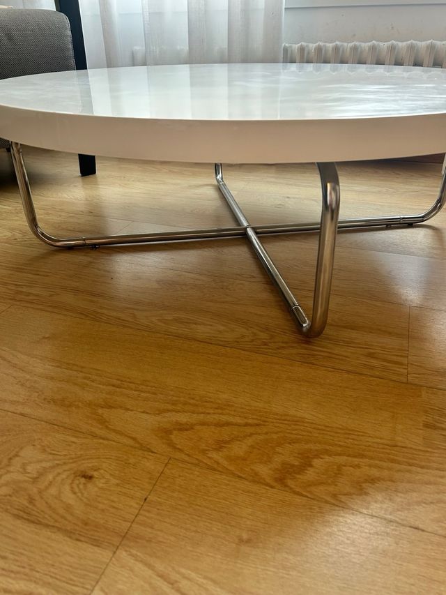 Mesa centro redonda blanca con patas de acero.