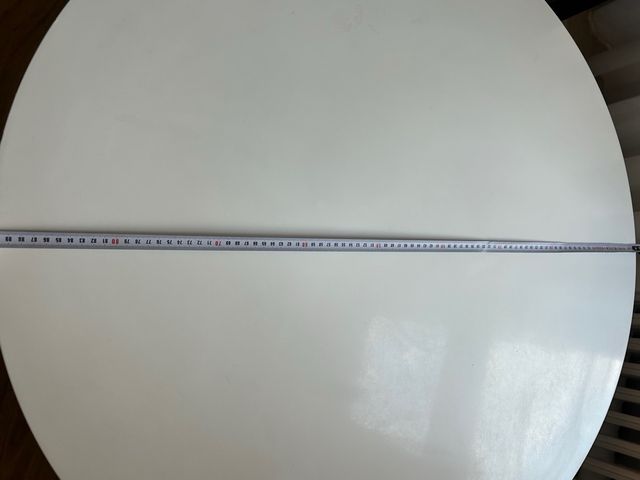 Mesa centro redonda blanca con patas de acero.