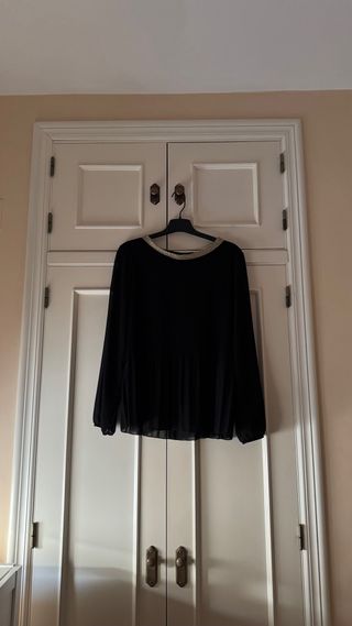 Blusa negra plisada con detalle dorado