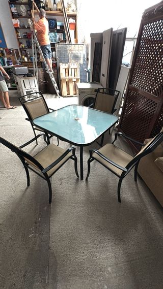 Mesa de terraza y 4 sillas de metal negro.
