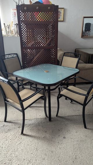 Mesa de terraza y 4 sillas de metal negro.