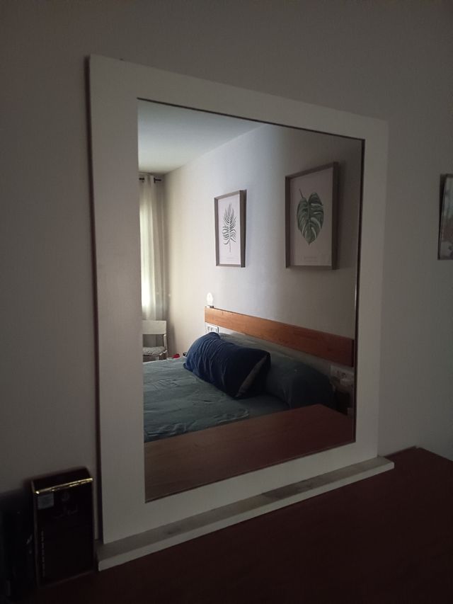 El marco del espejo esta pintado de blanco