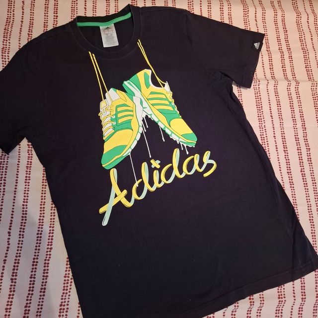 T-Shirt Adidas nera con stampa scarpe in giallo ve