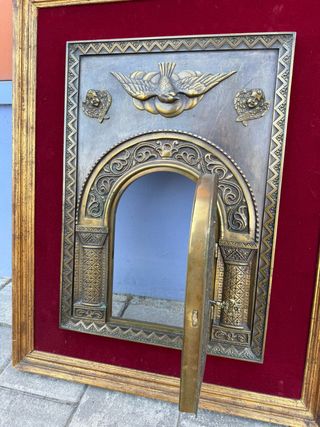 Porta del sagrario in bronzo incorniciata.