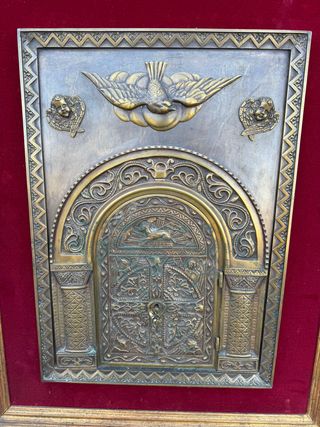 Porta del sagrario in bronzo incorniciata.