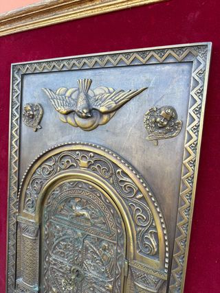 Porta del sagrario in bronzo incorniciata.