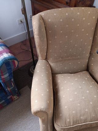 Sillón orejero beige con topos un poco más claros.