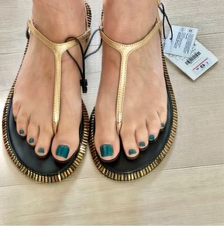 Sandalias doradas planas con la etiqueta.