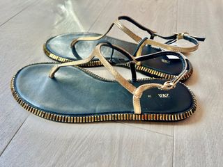 Sandalias doradas planas con la etiqueta.